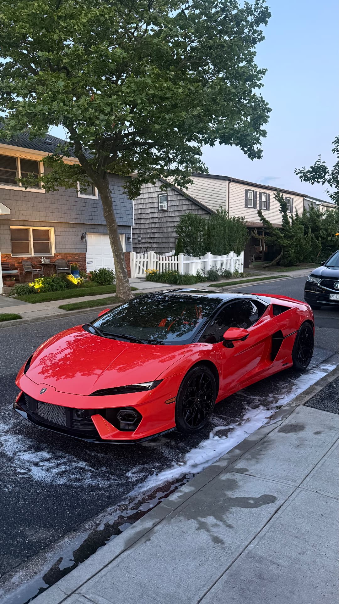 Red Lamborghini supercar after a foam wash at the curb
